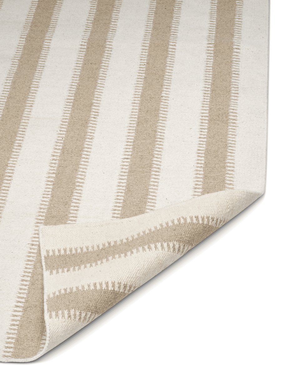 Area rug featuring beige and off-white vertical striped pattern with a folded corner, woven textured fabric.