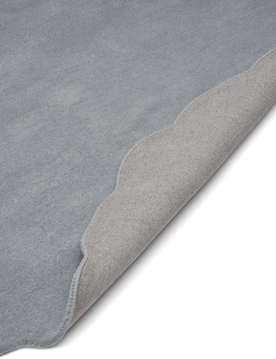 Ullmatta Shell Blå med vågformad kant. Detaljbild av ett uppvikt hörn.