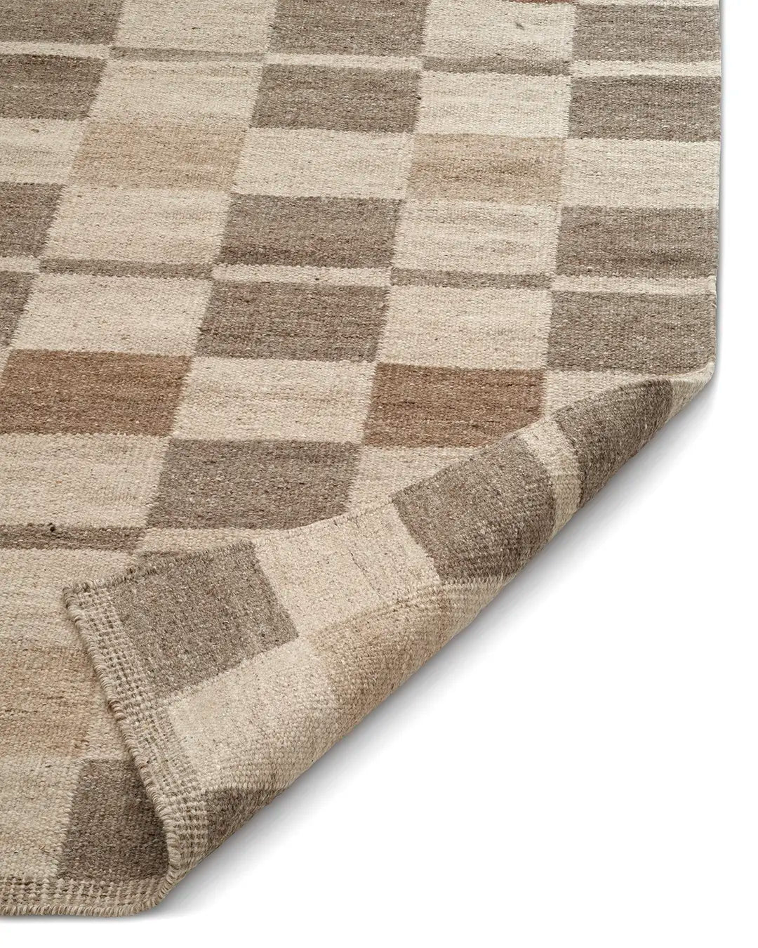 Tan and cream checkered area rug with a woven texture and folded corner detail.