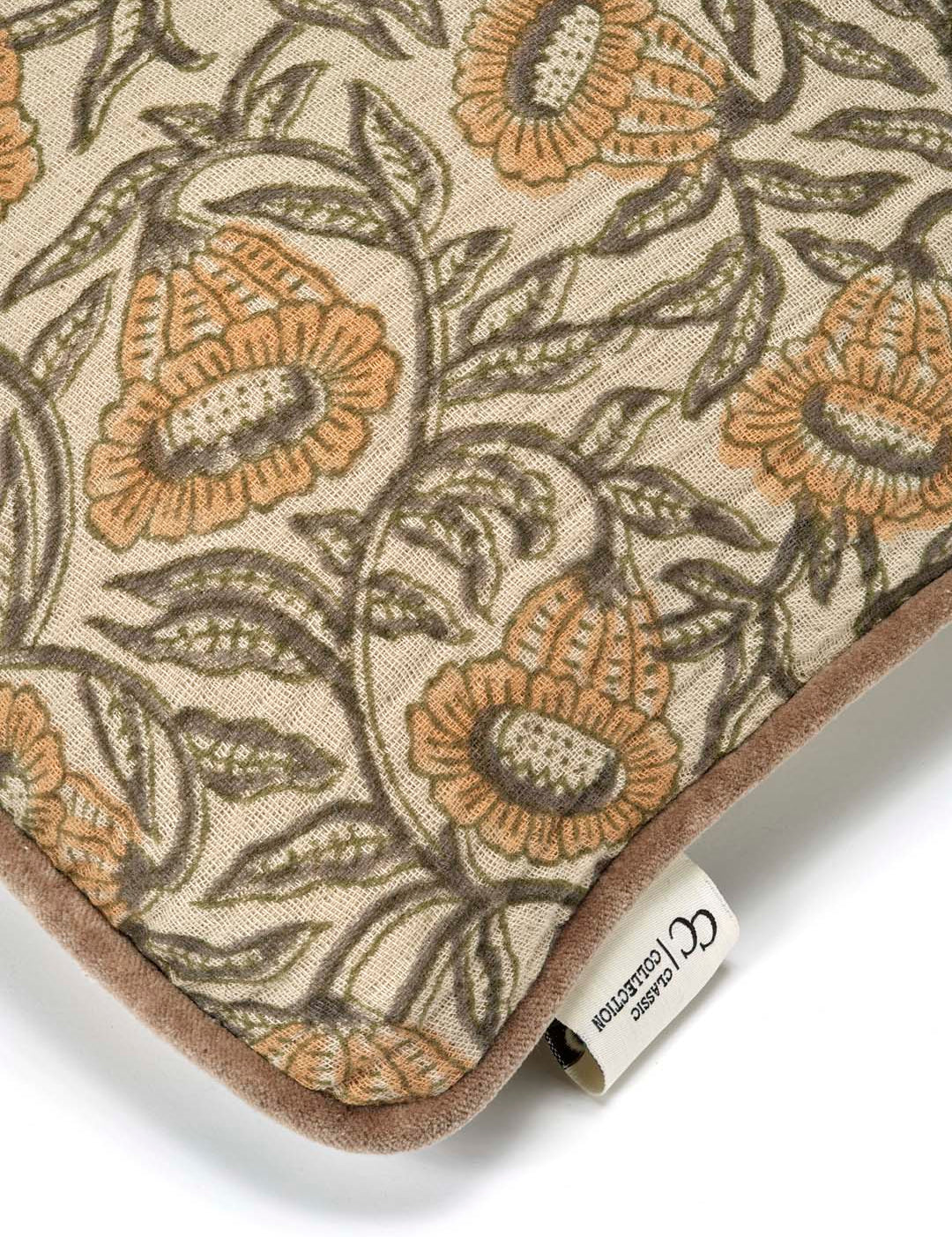 Kuddfodral Bell Yellow i handtryckt bomull med blommönster och pipingkant, frilagt mot vit bakgrund. Detaljbild av ett kuddhörn.