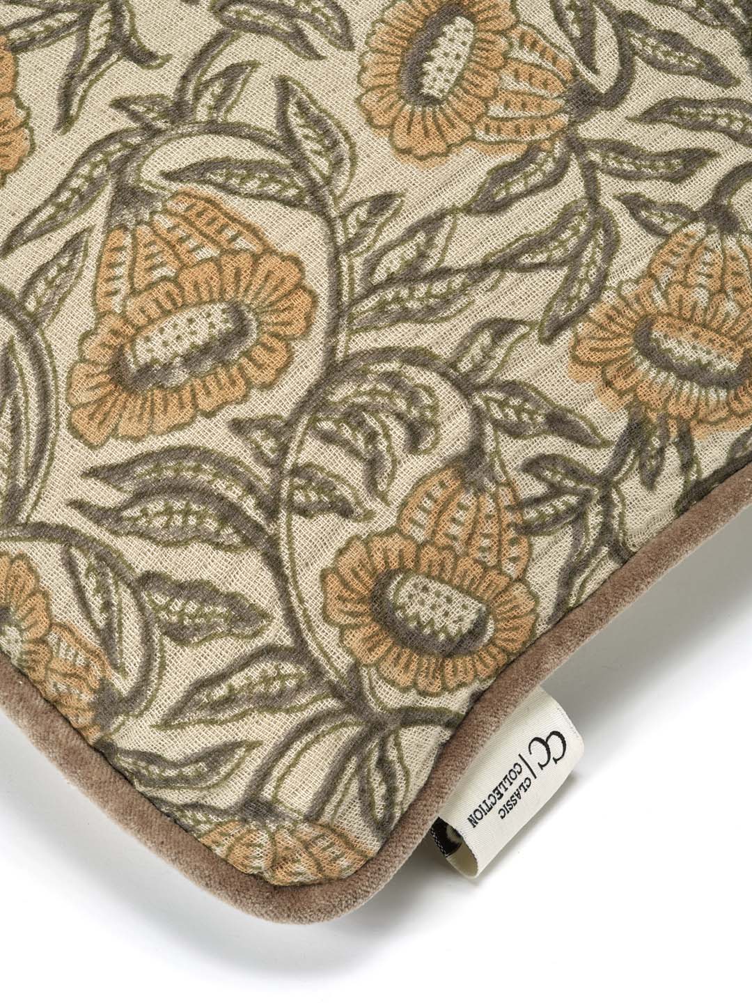 Kuddfodral Bell Yellow i handtryckt bomull med blommönster och pipingkant, frilagt mot vit bakgrund. Detaljbild av ett kuddhörn.