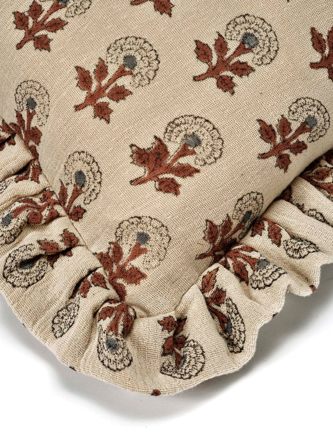 Kuddfodral Marigold Mocha i handtryckt bomull med mönster och volangkant, frilagt mot vit bakgrund. Detaljbild av ett kuddhörn.