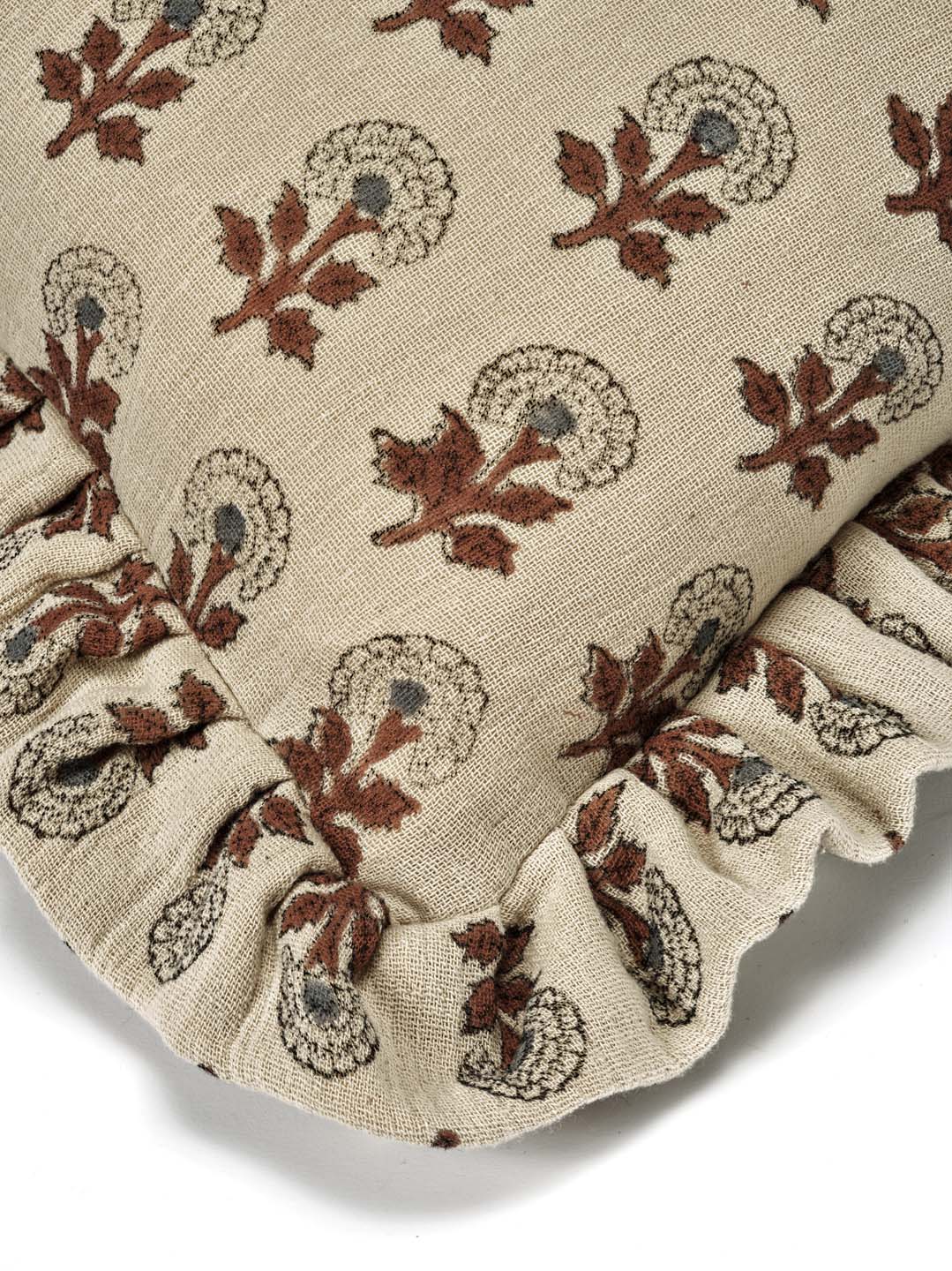 Kuddfodral Marigold Mocha i handtryckt bomull med mönster och volangkant, frilagt mot vit bakgrund. Detaljbild av ett kuddhörn.