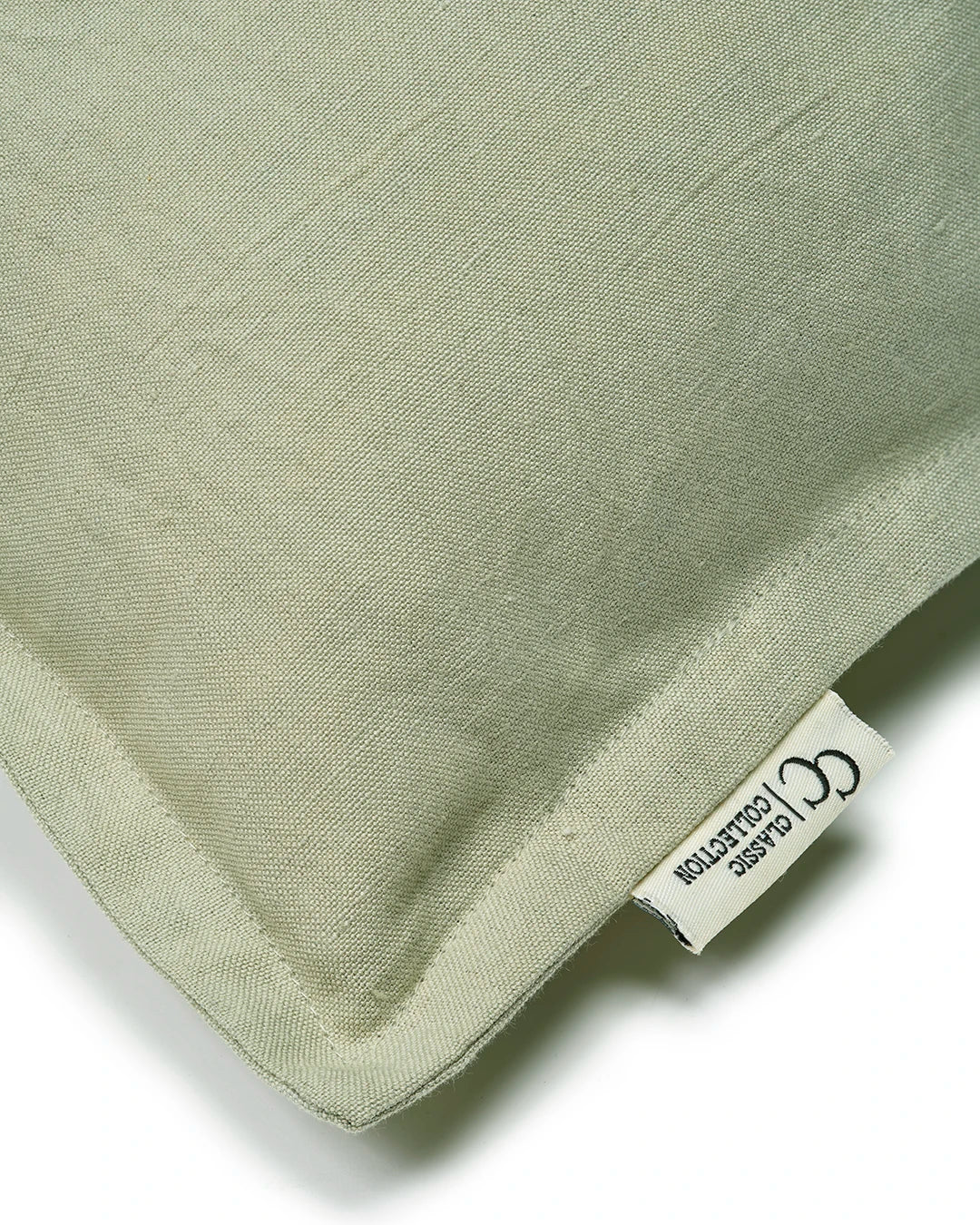 Närbild av kuddfodral Classic Linen Grön i linnetyg med kantdetalj och etikett från Classic Collection