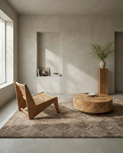 Modern living room with a natural wood cane chair, round burl wood coffee table, and beige textured geometric rug.