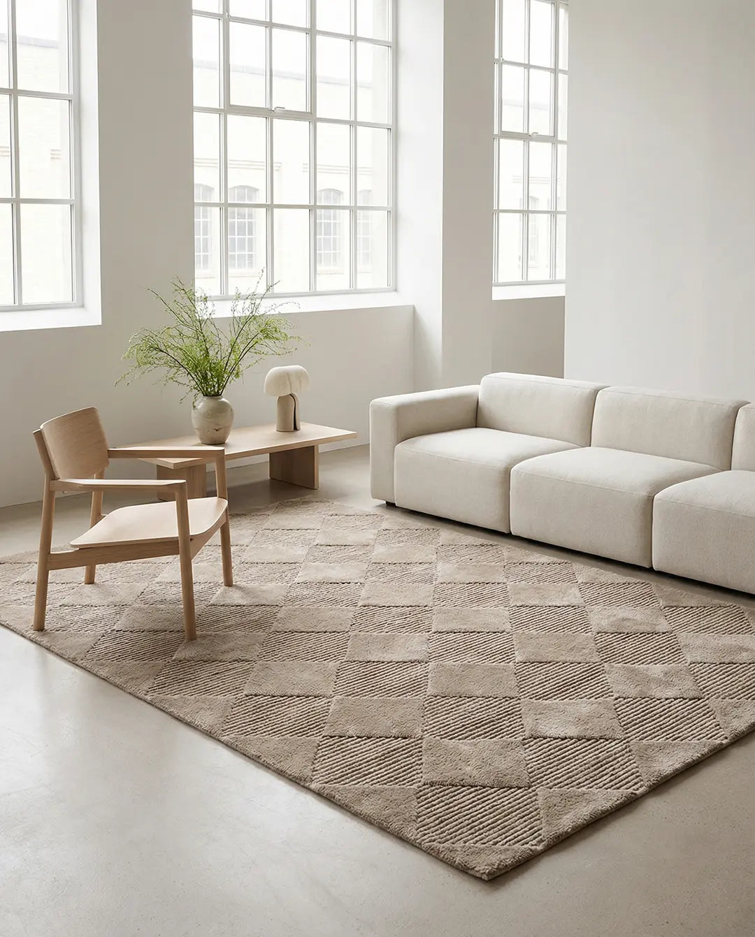 Beige rectangular area rug featuring a textured, geometric diamond pattern in a modern, minimalist living room.