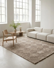 Beige rectangular area rug featuring a textured, geometric diamond pattern in a modern, minimalist living room.