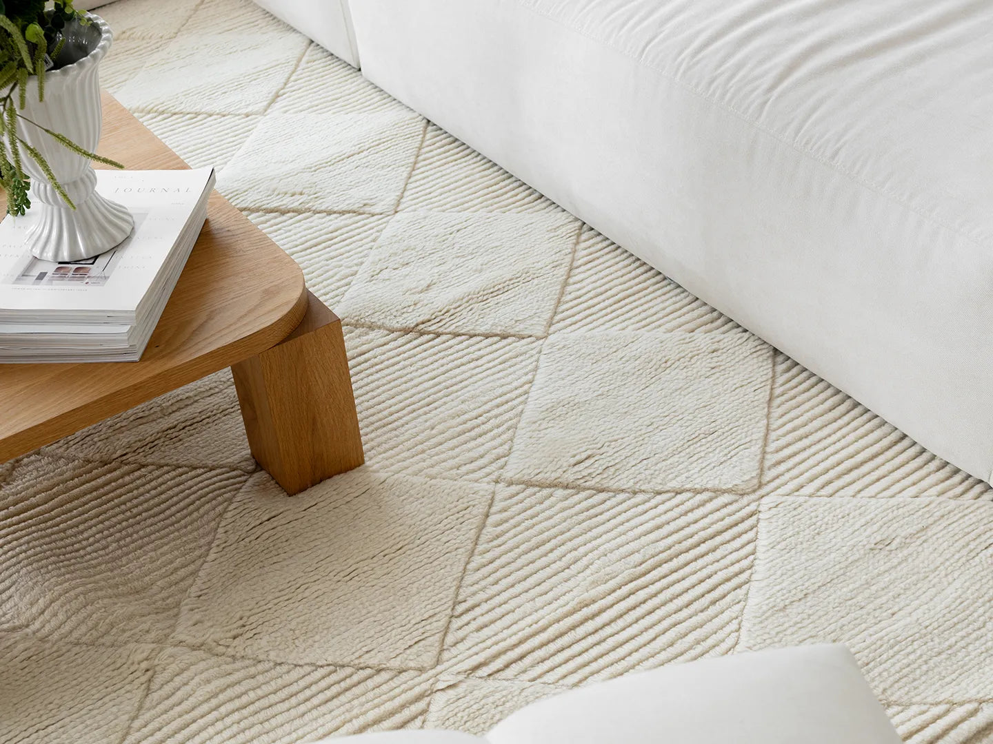 Detaljbild matta Berber Ivory, handvävd i vit ull med diskret rutmönster, placerad i ljust vardagsrum med soffor och träbord.