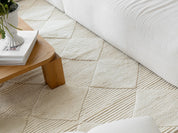 Detaljbild matta Berber Ivory, handvävd i vit ull med diskret rutmönster, placerad i ljust vardagsrum med soffor och träbord.