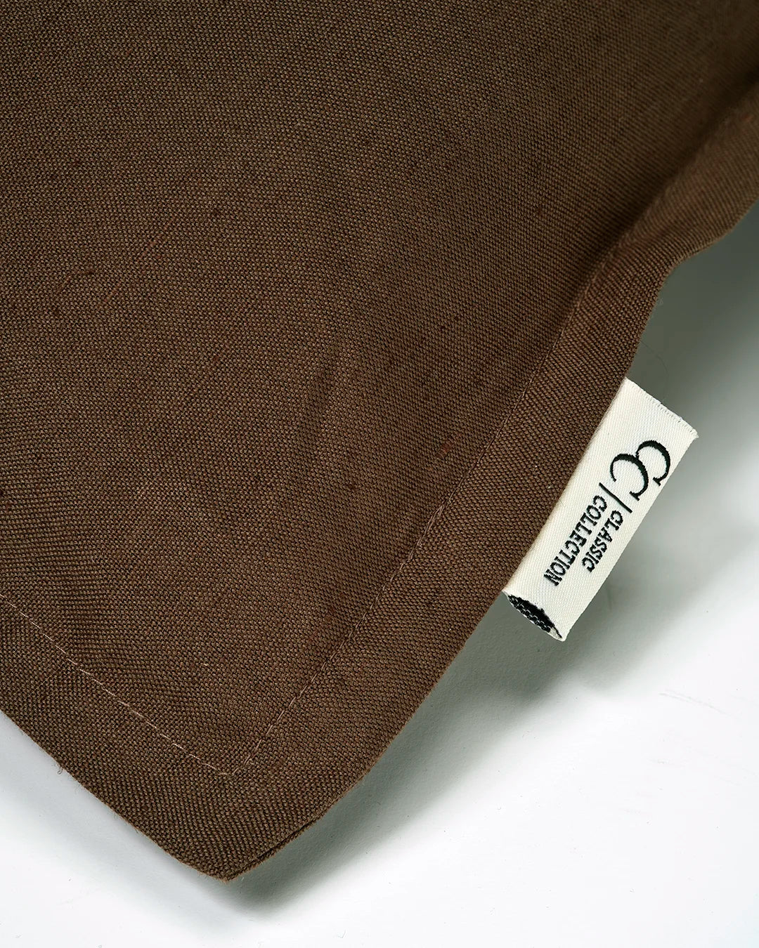 Kuddfodral Classic Linen Brun från Classic Collection i linne- och bomullsblandning, detaljbild av tygstruktur, söm och etikett.