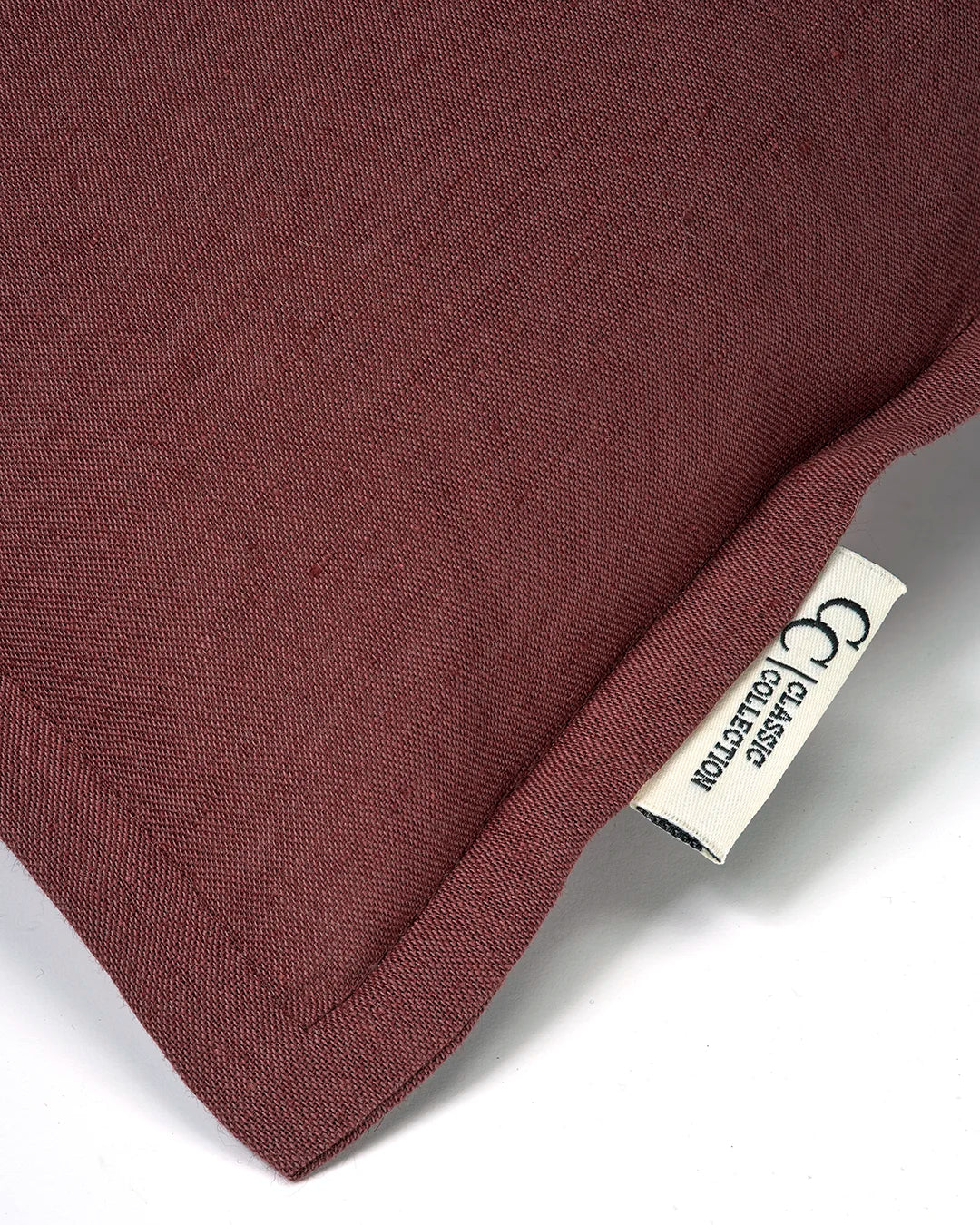 Kuddfodral Classic Linen Burgundy från Classic Collection i linne- och bomullsblandning, detaljbild av tygstruktur, söm och etikett.