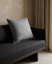 Kuddfodral Classic Linen Duvblå 50x50 cm från Classic Collection i enfärgat linne, stylat på en mörkgrå soffa i en varm, neutral interiör.
