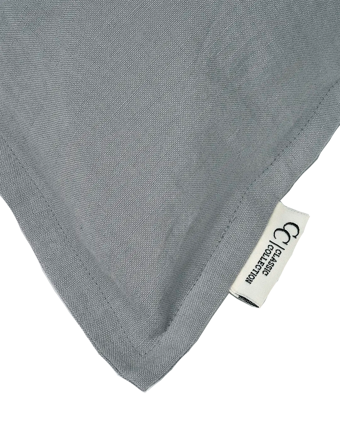Close-up of a grey linen throw pillow cover with a stitched edge and Classic Collection brand label.