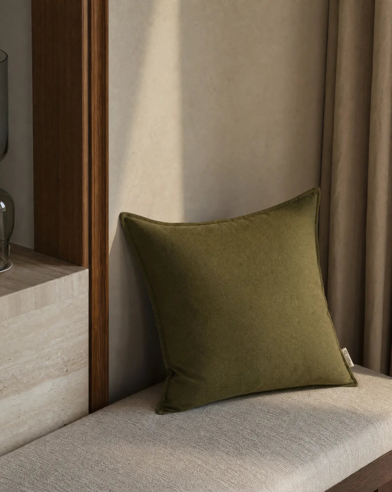 Kuddfodral Classic Linen Skogsgrön 50x50 cm från Classic Collection i enfärgat linne, stylat på en ljus bänk i en varm, neutral interiör.