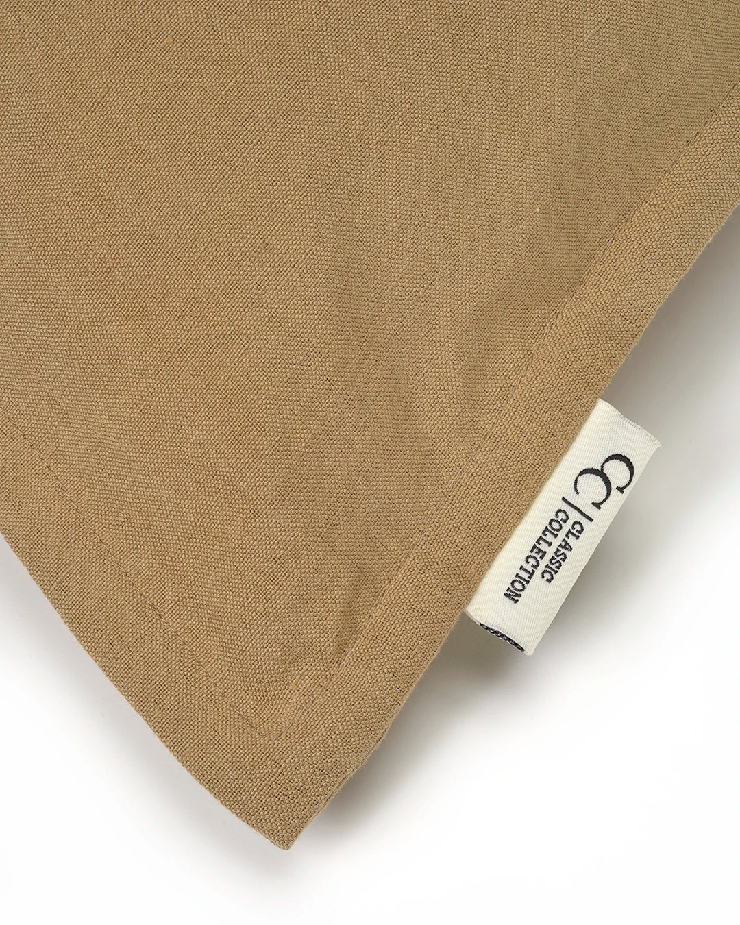 Tan woven fabric pillow cover with a Classic Collection brand label tag.