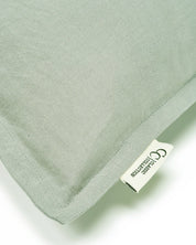 Close-up of a sage green linen throw pillow with a flange edge and a Classic Collection brand label.