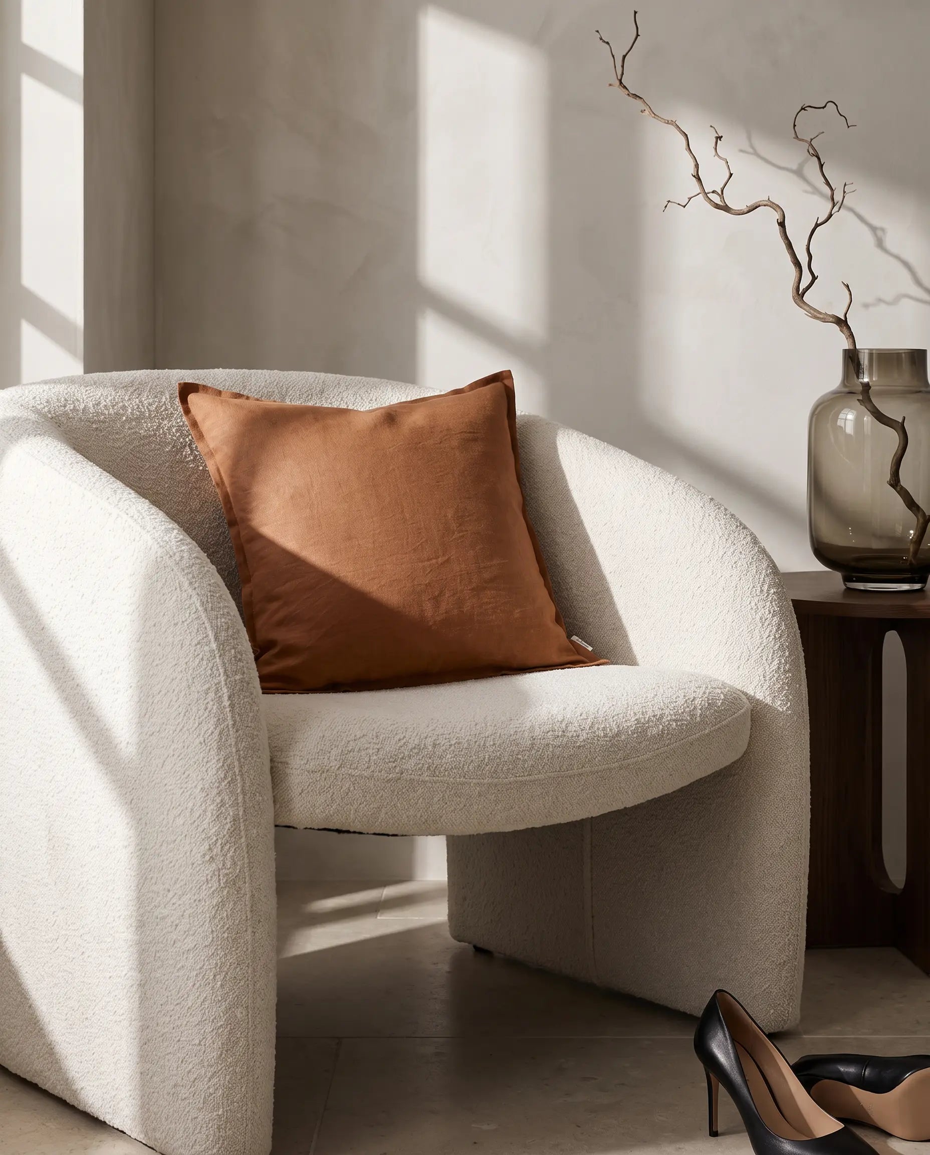Kuddfodral Classic Linen Terracotta 50x50 cm från Classic Collection i enfärgat linne, stylat i en ljus fåtölj i en varm, neutral interiör.