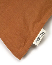 Close-up of a textured terracotta brown linen pillowcase with a white Classic Collection brand label.