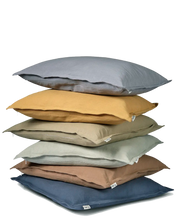 Stack of six square linen throw pillows in assorted neutral and earth tones on a white background.