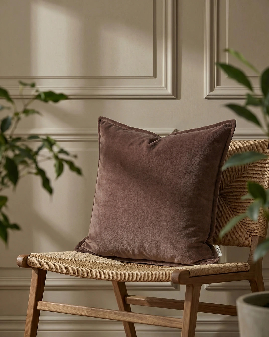 Kuddfodral Classic Velvet Brun från Classic Collection i mjuk sammet, 50x50 cm, placerat på en vävd trästol.