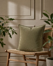 Kuddfodral Classic Velvet Grön från Classic Collection i mjuk sammet, 50x50 cm, placerat på en vävd trästol.