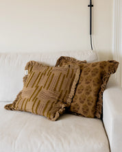 Kuddfodral Lines Amber och Chandra Amber i handtryckt bomull med mönster och volangkant, placerade tillsammans i en soffa i hemmiljö.