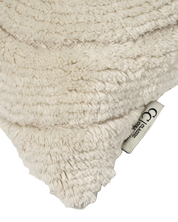 Detalj av Kudde Swirl Off-white i ull. Närbild som visar det tuftade, organiska swirlmönstret med tydlig relief, den vävda basen samt Classic Collection-etikett i sidan.
