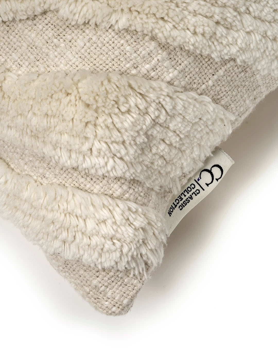 Cream-colored textured throw pillow with shaggy striped pattern and a Classic Collection brand tag.