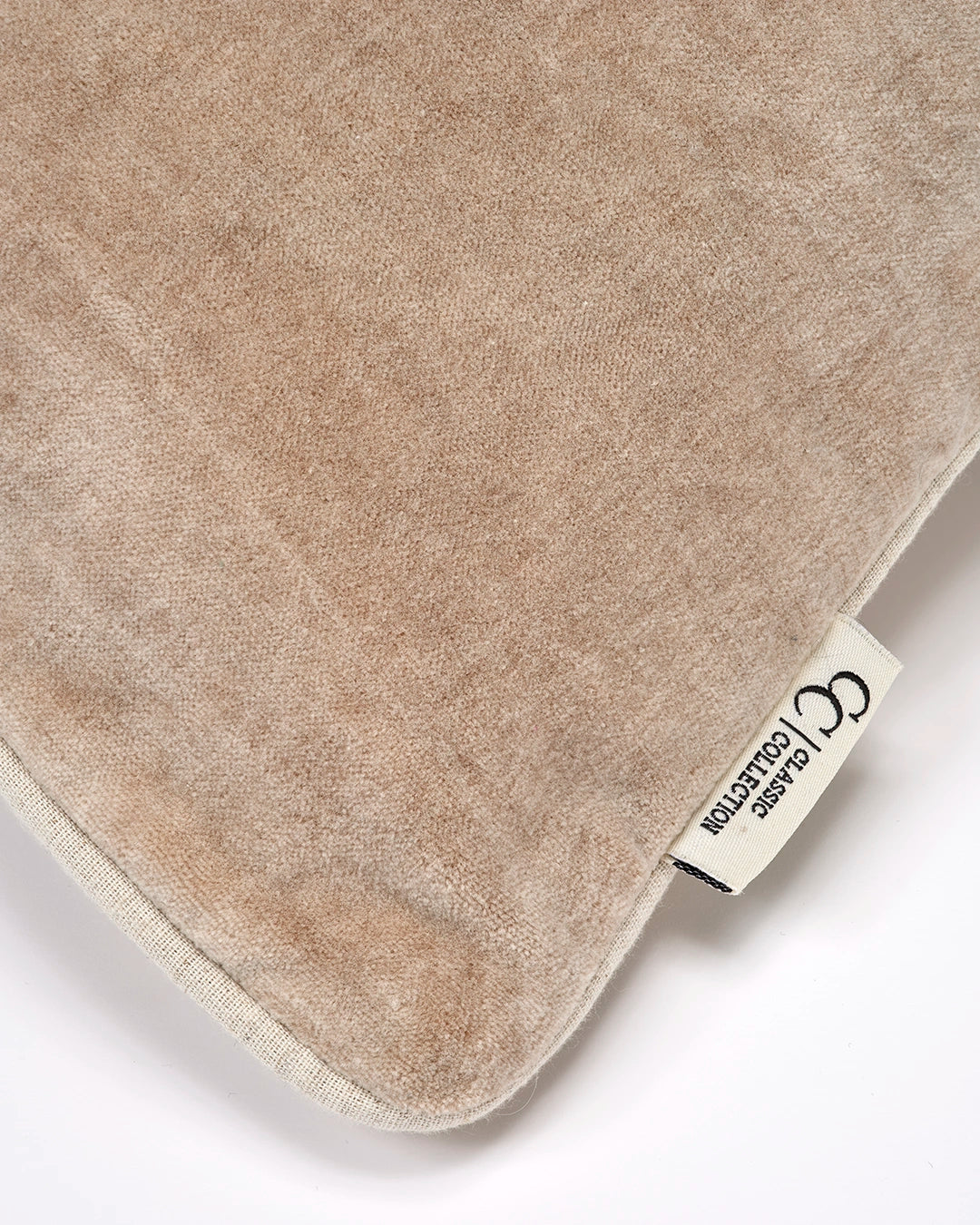 Närbild av Classic Velvet kuddfodral i ljus beige bomullssammet med tvättad yta, passpoalkant och synlig Classic Collection-etikett.