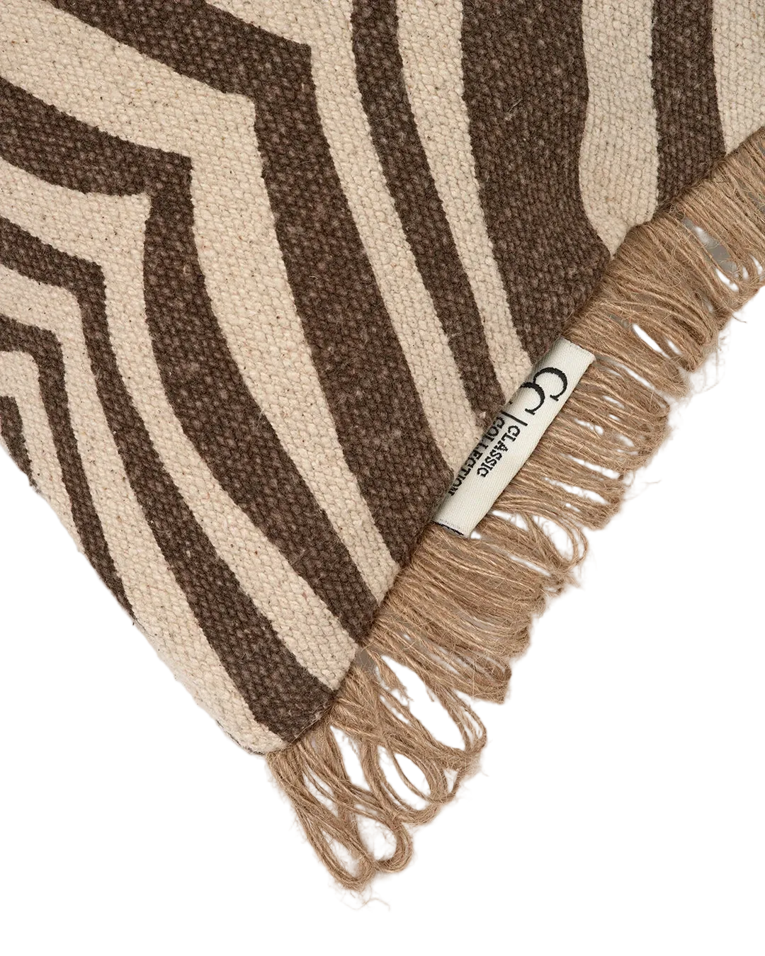 Kudde Zebra Brun i bomull med zebramönster i brunt och natur, dekorativ frans i jute längs kanterna, frilagd produktbild av ett hörn på kudden mot ljus bakgrund.