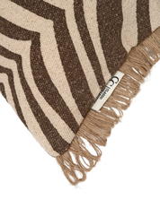 Kudde Zebra Brun i bomull med zebramönster i brunt och natur, dekorativ frans i jute längs kanterna, frilagd produktbild av ett hörn på kudden mot ljus bakgrund.