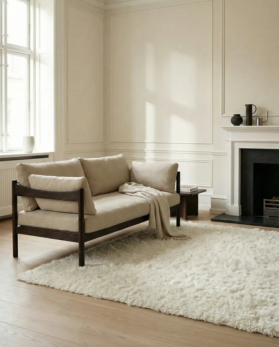 Modernes Zweisitzer-Sofa mit beigem Leinenbezug und dunklem Holzgestell in einem hellen Wohnzimmer.