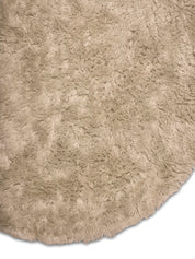 Detaljbild av rund ullmatta Cloudy i beige rya som visar luggens struktur och mattans runda form