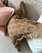 Kudde Chandra Amber i blockprintad bomull med sammetskant, placerad i soffa tillsammans med enfärgad kudde.