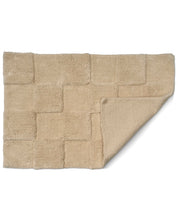 Beige badrumsmatta Check i bomull, 60x90 cm, med uppvikt hörn som visar mattans struktur och baksida.