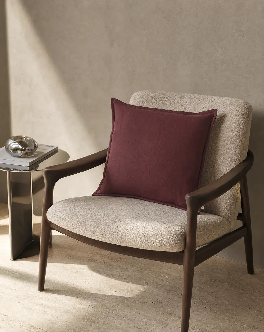 Kuddfodral Classic Linen Burgundy 50x50 cm från Classic Collection enfärgad i linne-bomullblandning. Stylat i en beige fåtölj i en varm, elegant interiör.