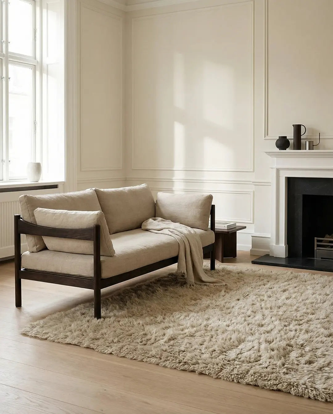 Beiges Sofa aus Leinen mit dunklem Holzrahmen und passender Decke in modernem, hellem Wohnzimmer.