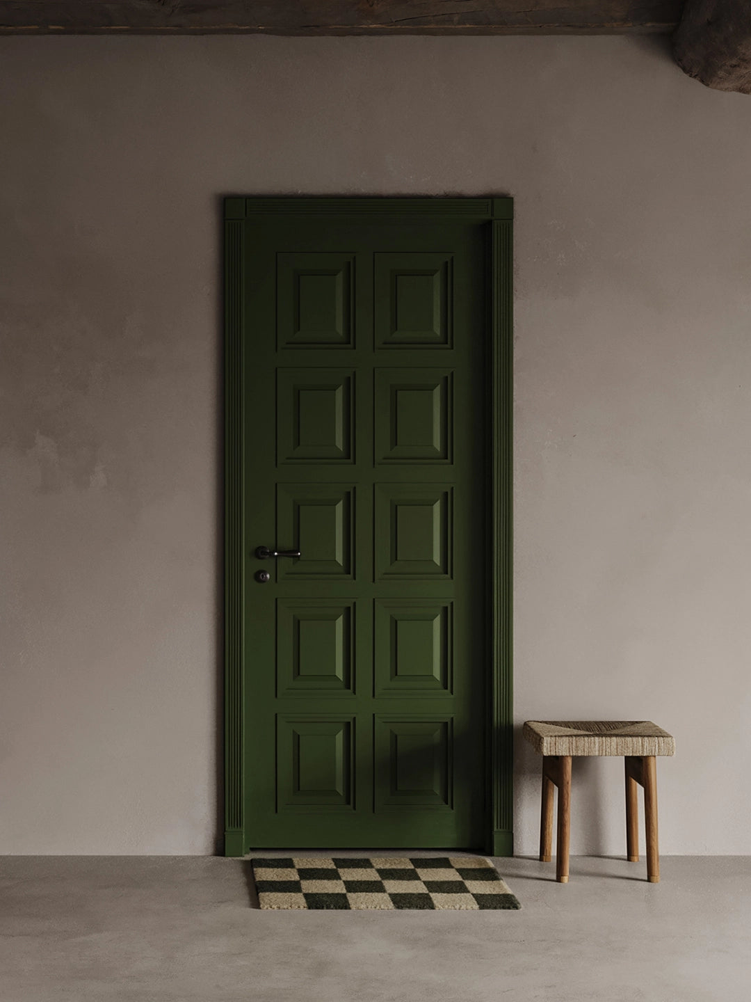 Dörrmatta Square Skogsgrön/Natur i ull framför grön dörr och vägg i neutral ton, med liten pall i trä och naturmaterial bredvid.