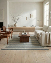 Grå och beige randig matta i ett modernt vardagsrum med läderfåtöljer och vit soffa.