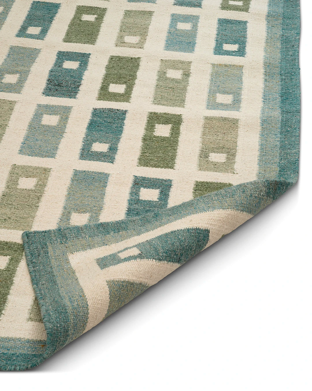 Detalj av Röllakan Fyrbo Teal i ull med flatvävd struktur, teal kant och grafiskt rutmönster; hörn vikt för att visa tjocklek och baksida.