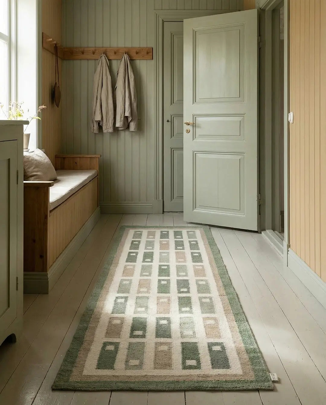 Moderner Flurläufer mit geometrischem Rechteck-Muster in Salbeigrün und Beige auf hellem Holzboden.