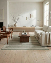 Grå mönstrad matta i ett ljust vardagsrum med beige soffa, läderfåtöljer och ett soffbord i trä.