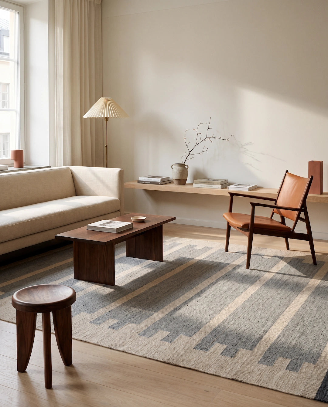 Blå och beige flatvävd ullmatta Falsterbo i ett ljust vardagsrum med soffa, fåtölj och soffbord.