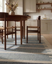 Randig matta i blått och beige under ett runt matbord i trä med stolar i en stilren köksmiljö.