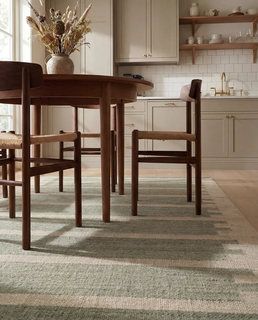 Grön och beige randig matta i ull under ett runt matbord i mörkt trä med stolar i skandinavisk stil.