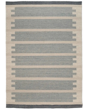 Vävd matta med geometriskt mönster i blått och beige, perfekt för en modern inredning.