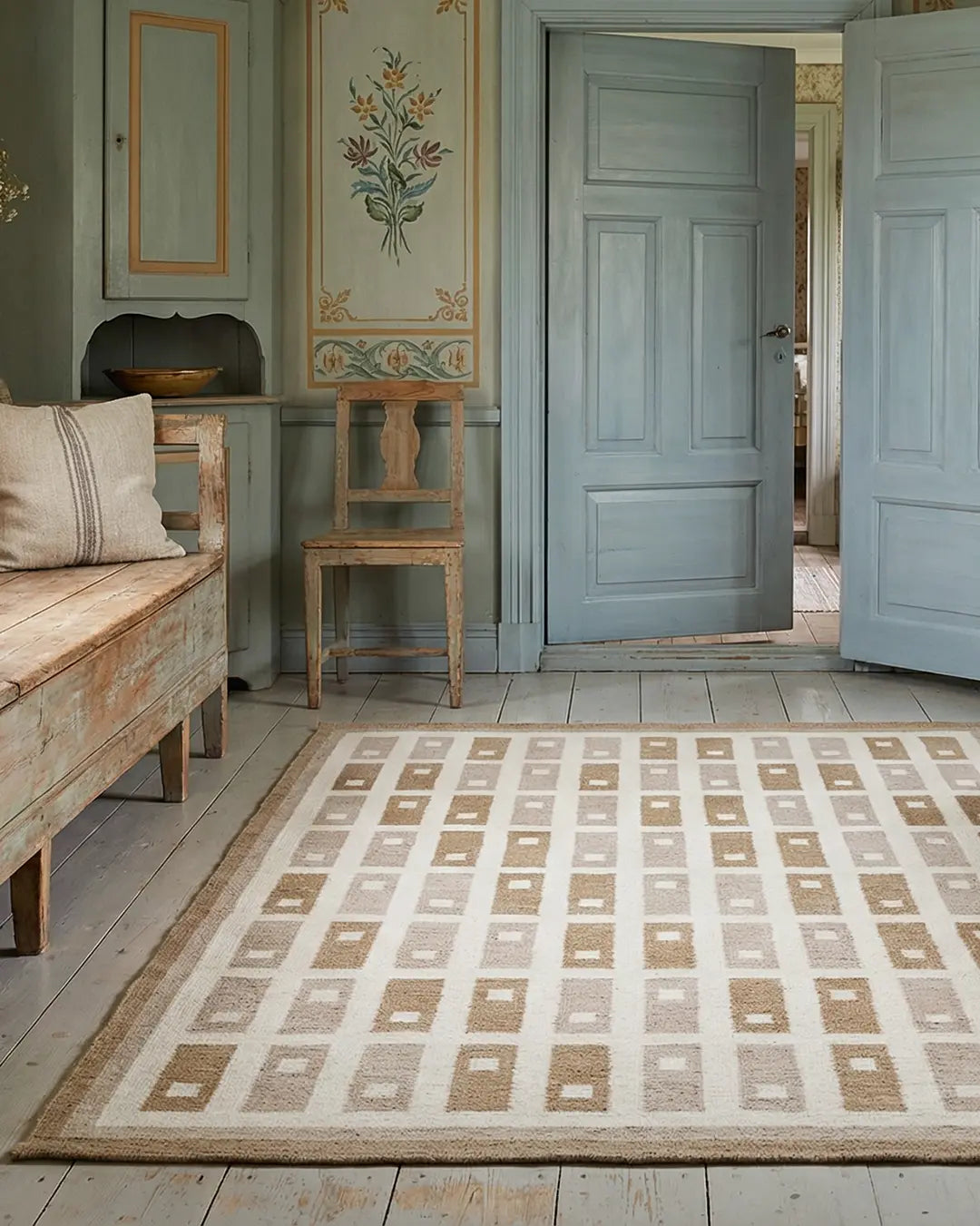 Rektangulär matta med geometriskt rutmönster i beige och naturtoner, placerad i ett rustikt rum med trägolv.