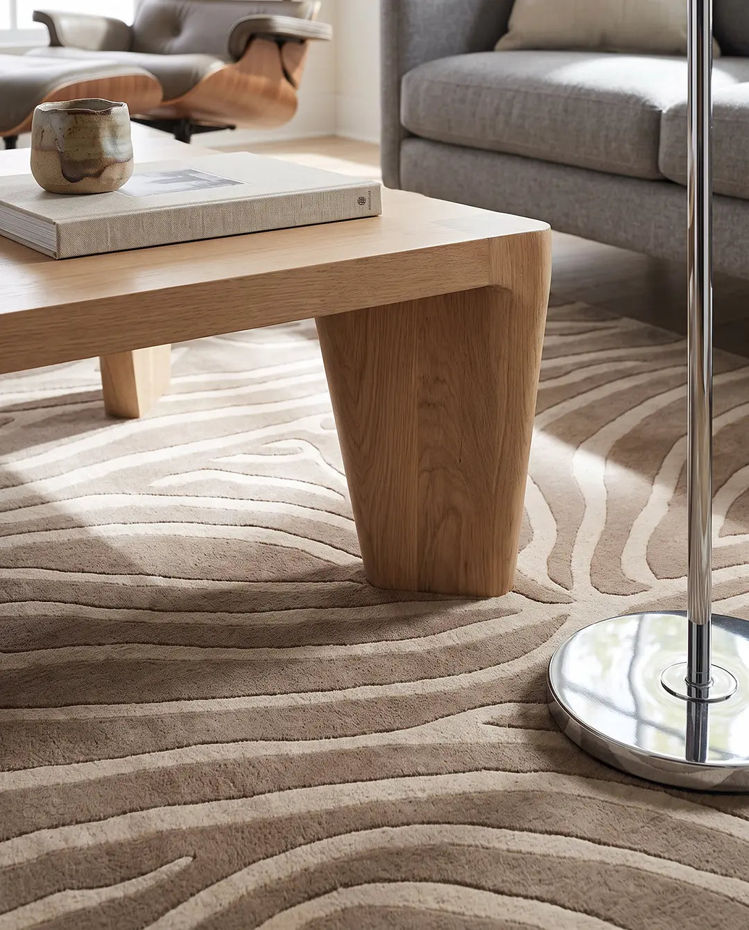 Närbild på den handtuftade ullmattan Zebra Beige från Classic Collection med mjukt zebramönster i beige och off-white under ett soffbord i trä.