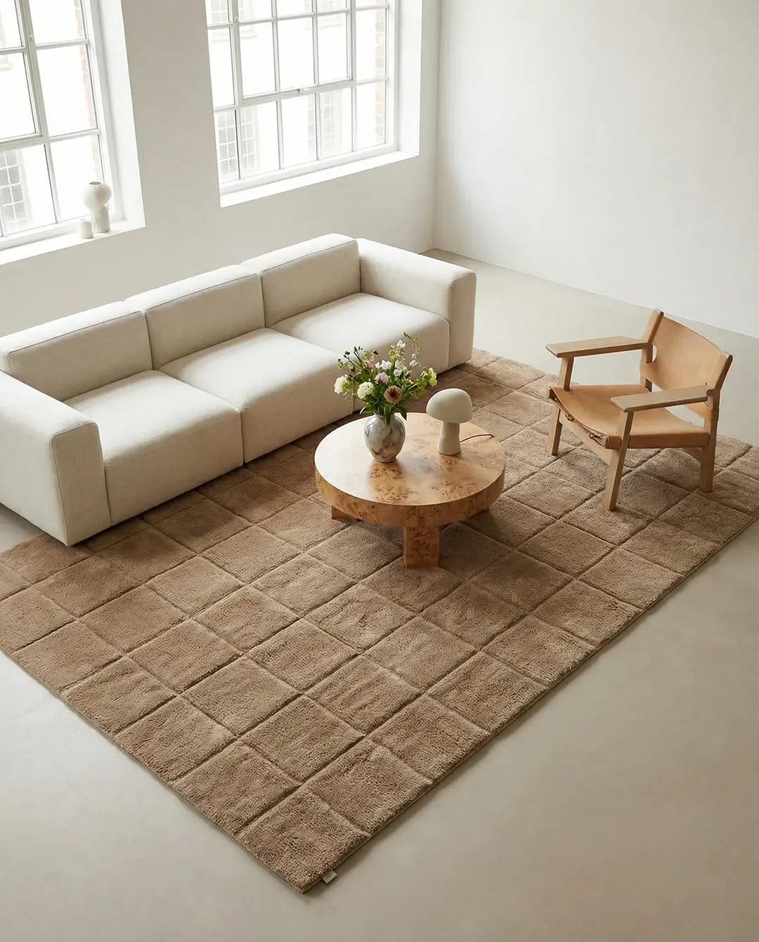 Beige tufted area rug with a square grid pattern in a modern living room with a cream sofa and wooden furniture.