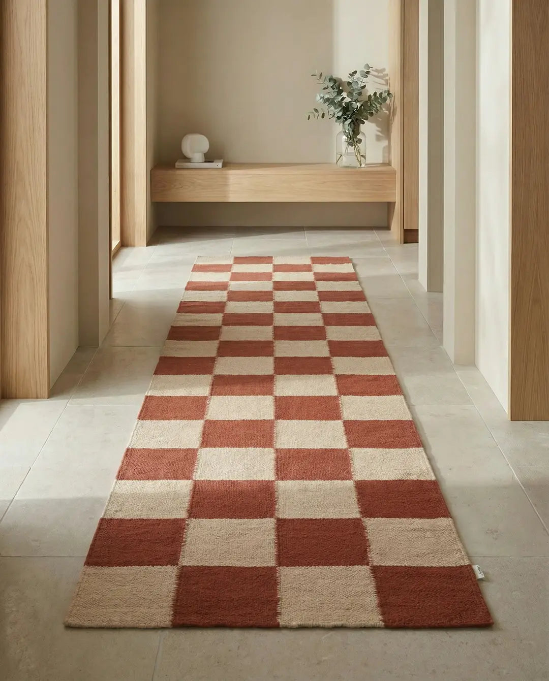 Langer Flurläufer mit modernem Schachbrettmuster in Terrakotta und Beige auf einem Fliesenboden im Flur.